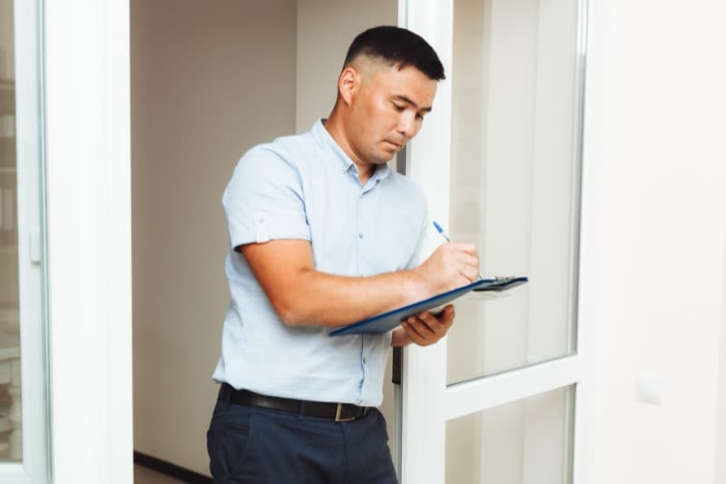 Property inspector with clipboard documenting property condition